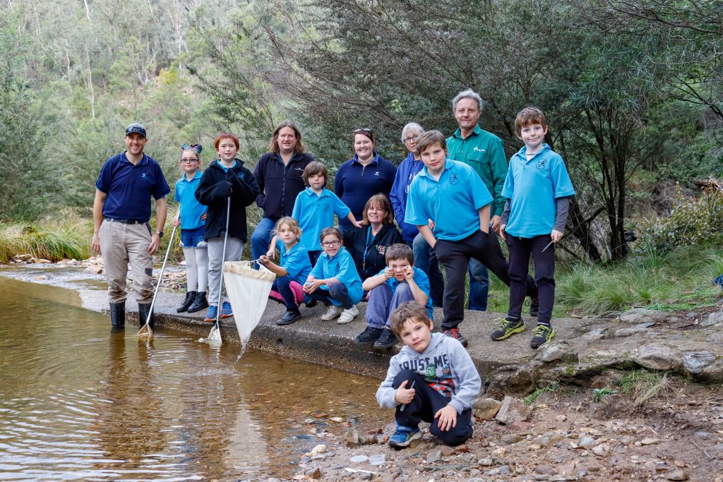 Members of the EGCMA, Greening Australia amd Bug Blitz stand alongside students of Clifton Creek Primary on the banks of the Nicholson River at Deptford.