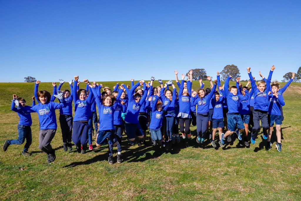 Students of Lindenow Primary jump for joy on a grassy hill near Skull Creek.