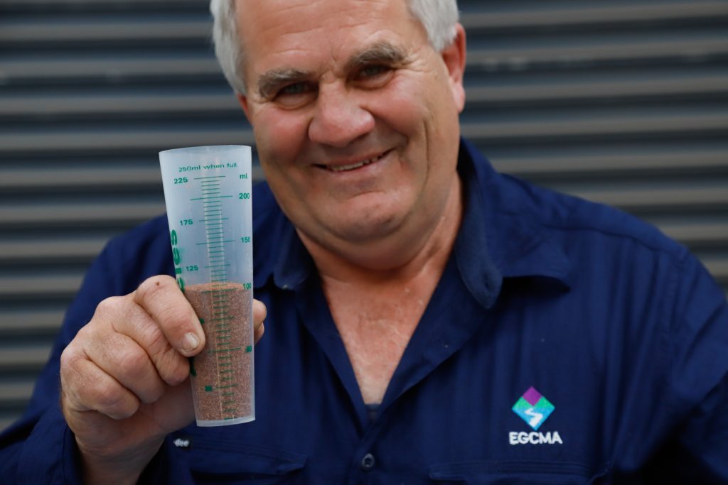 EGCMA Works Coordinator Peter Brookes holds a plastci container full of seed ready to be planted.